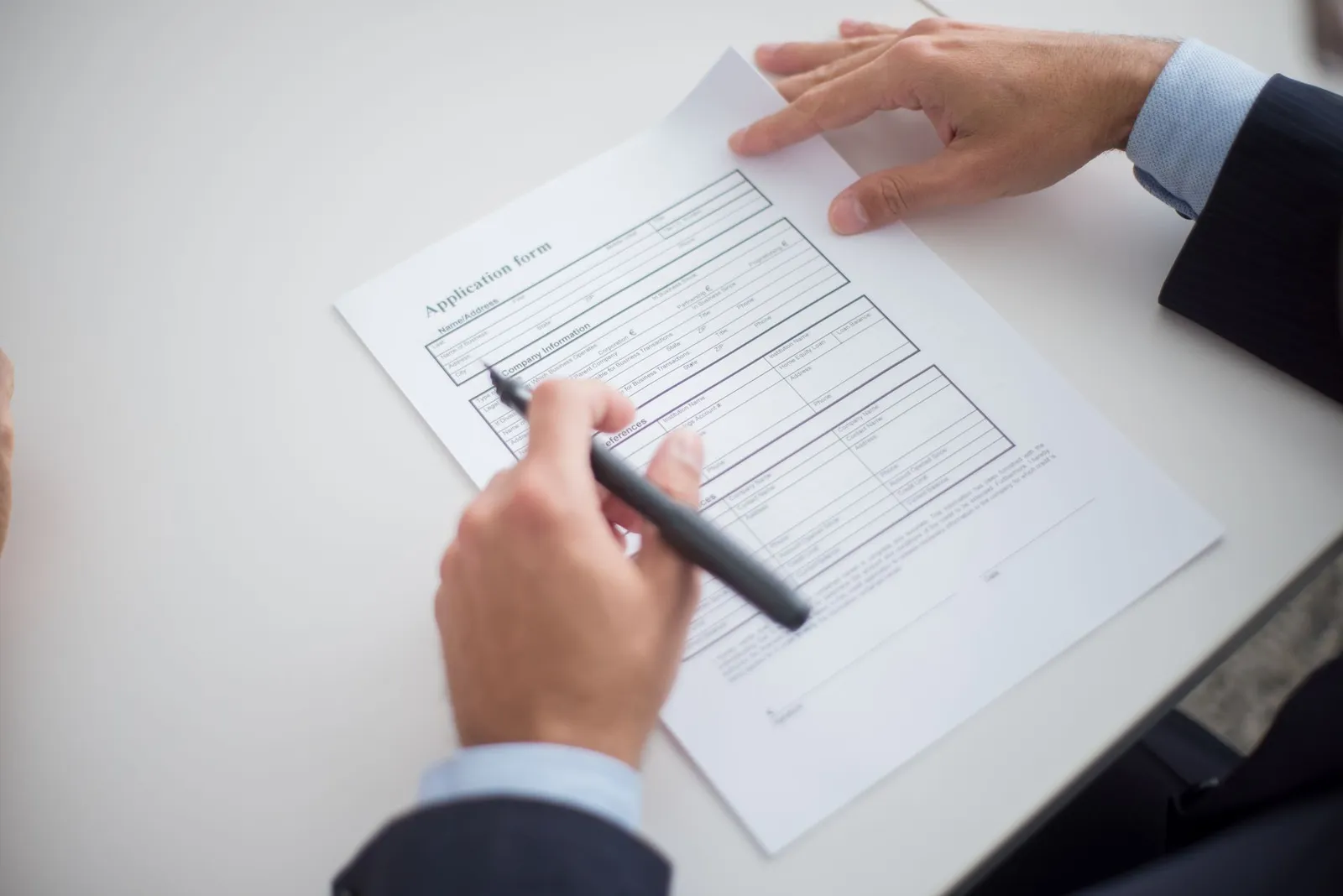Hands holding a pen over a printed application form, checking AI degree requirements