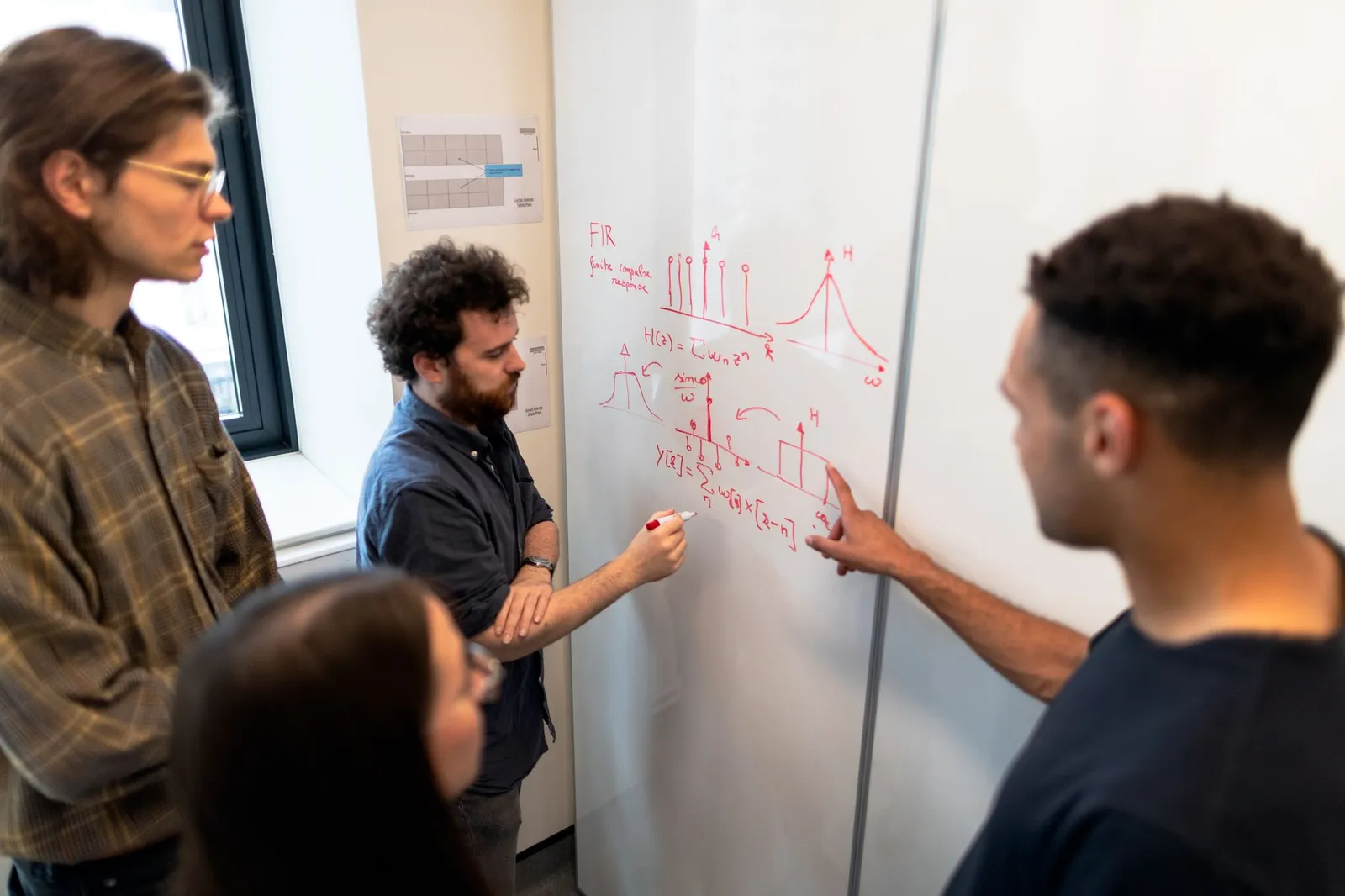 AI research scientists at a whiteboard as one sketches a signal processing derivation