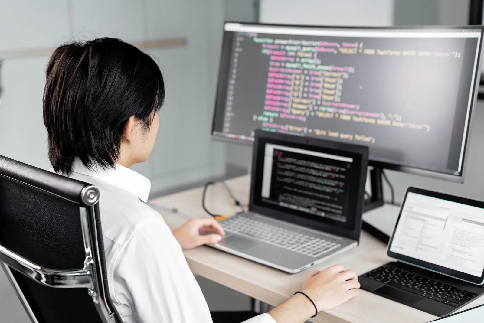 Person coding across a monitor, laptop and tablet while preparing for AWS machine learning engineer associate
