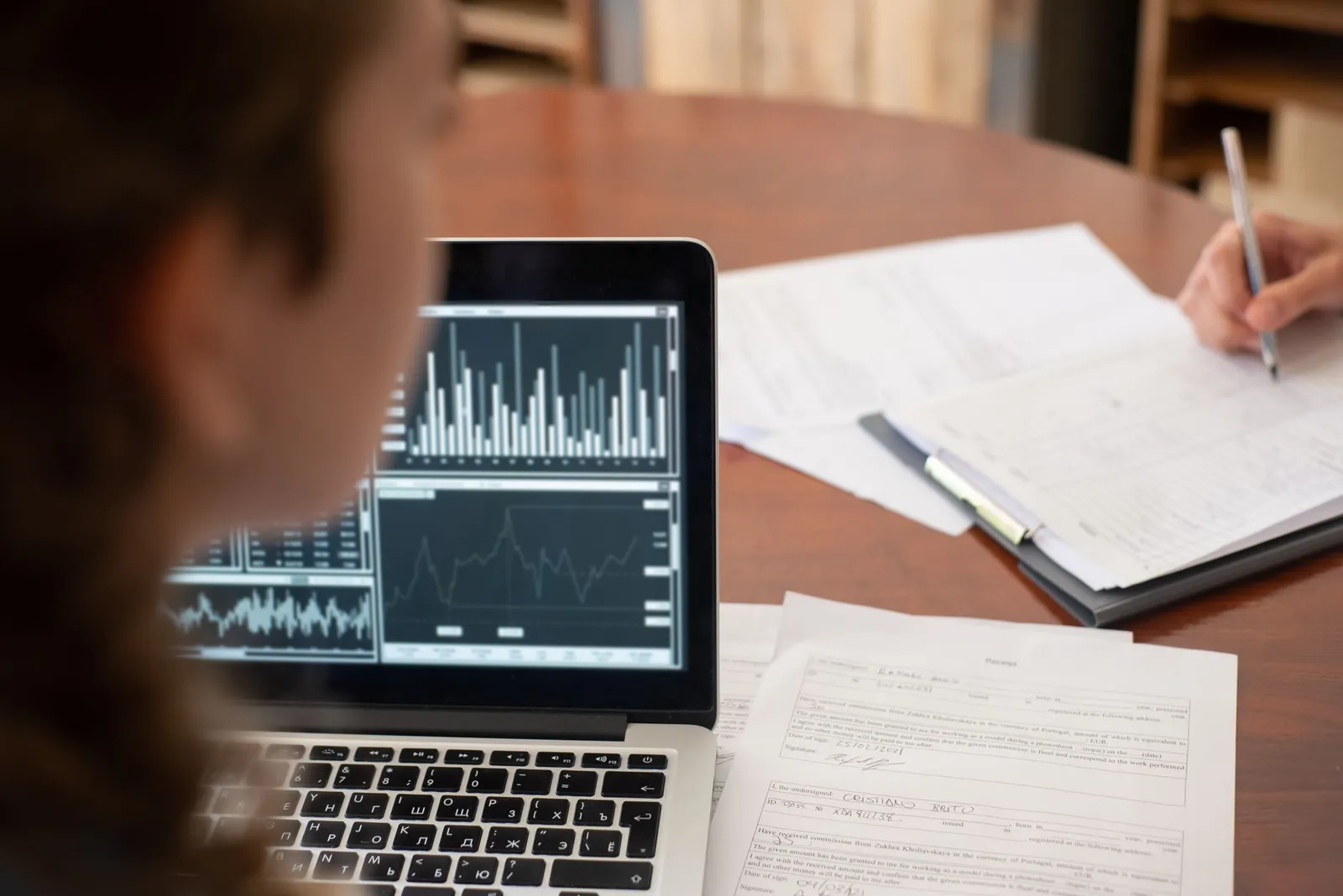Data scientist reviewing bar and line charts on a laptop beside handwritten notes