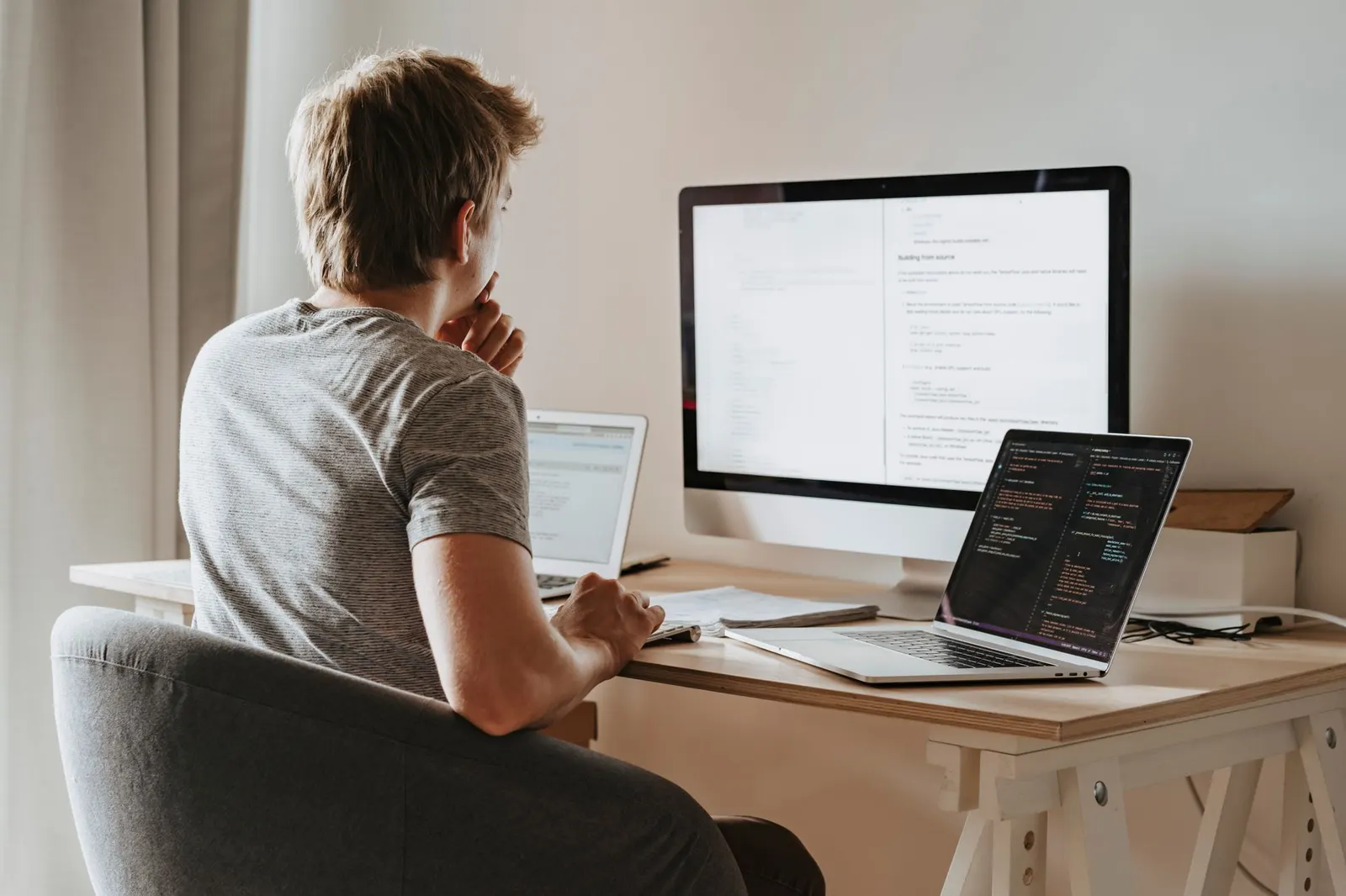 Man reading on a large monitor beside a code laptop, studying for Google Cloud professional machine learning engineer