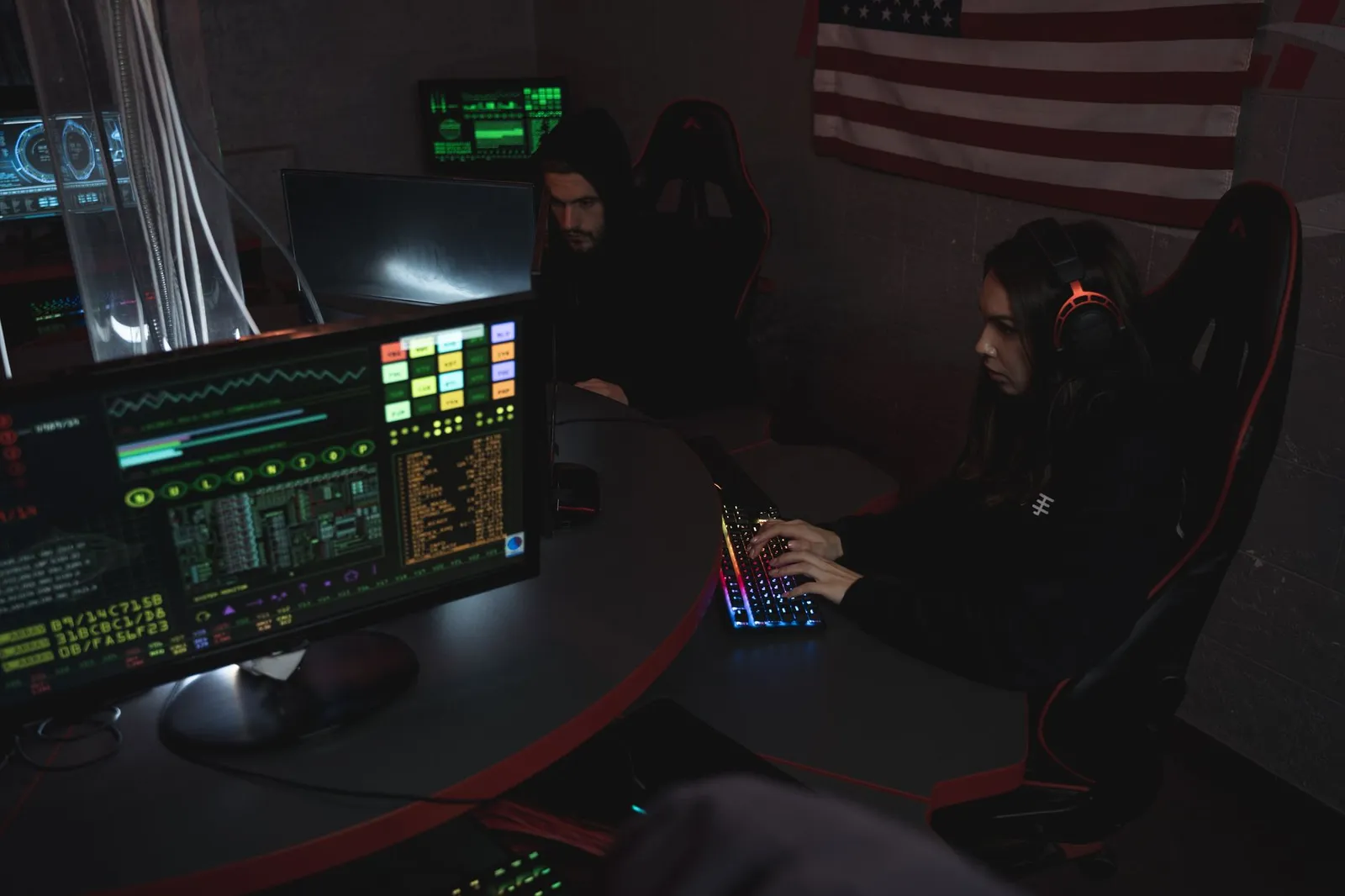 Information security analyst typing at a desk with glowing monitors in a dim room