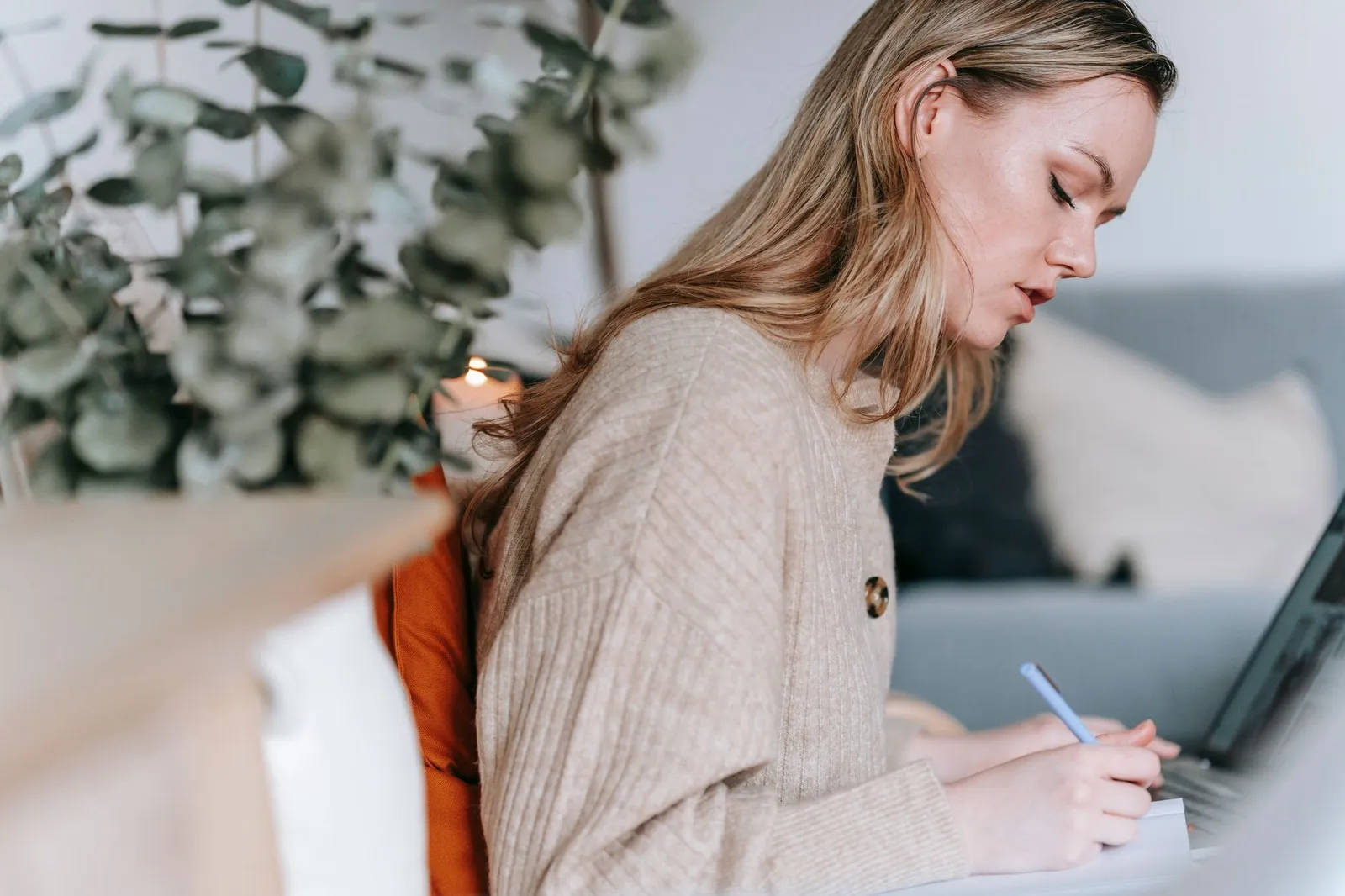 Woman writing in a planner beside a laptop, weighing whether an AI degree is worth it