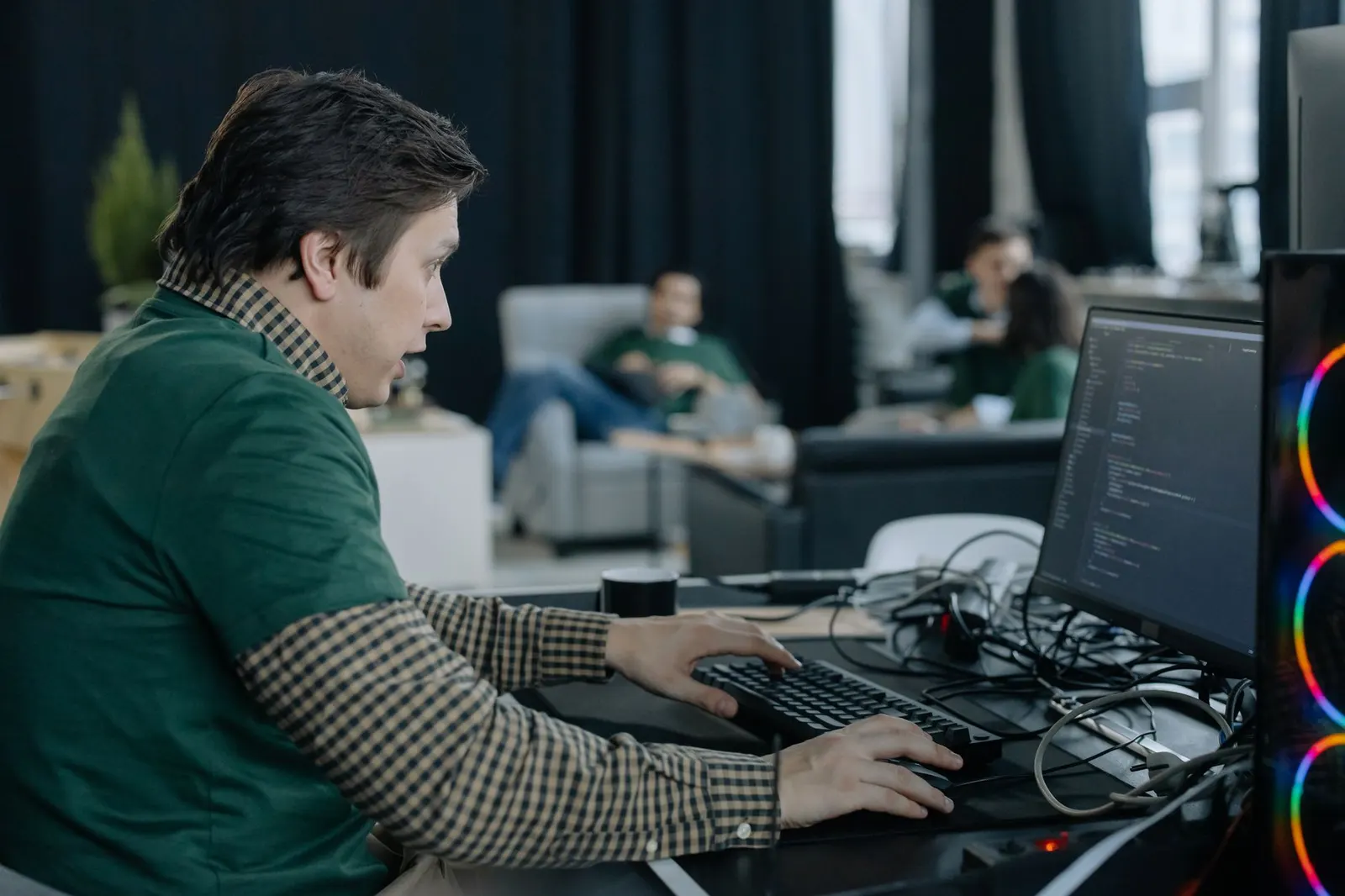 Machine learning engineer typing at a monitor full of code in an open-plan office