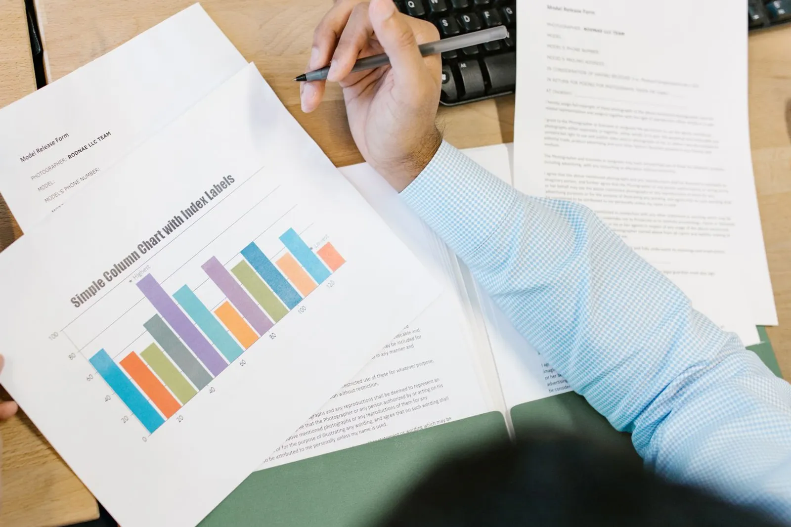 Hand holding a pen over a printed bar chart, showing how we rank online AI degrees
