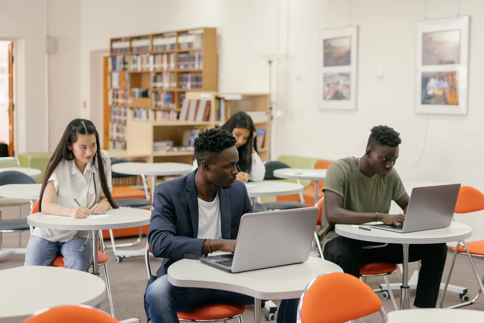 Students working on laptops at classroom tables while comparing AI degree programs